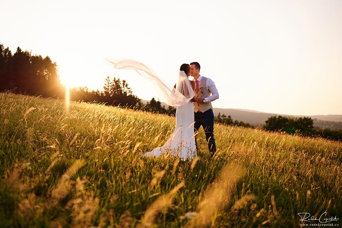 svatební fotka nevěsty se závojem při západu slunce v přírodě