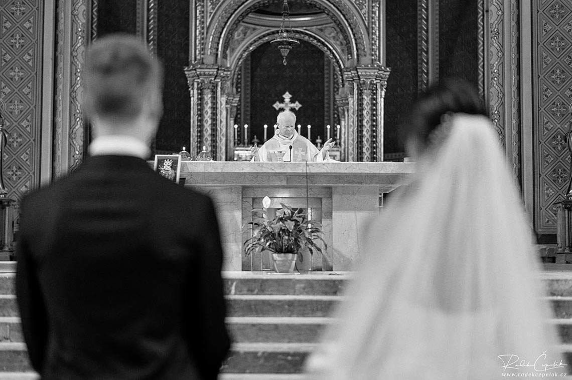černobílá svatební fotografie kněze během obřadu