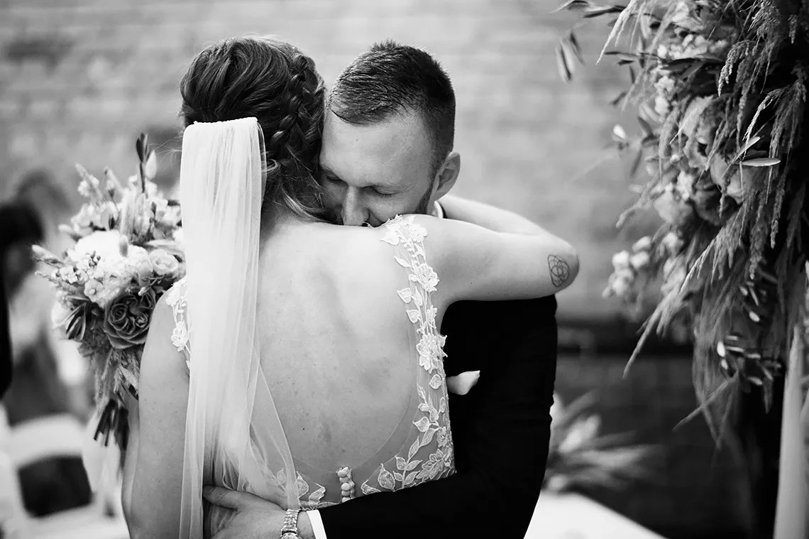 ženich a nevěsta se objímají po svatebním obřadu