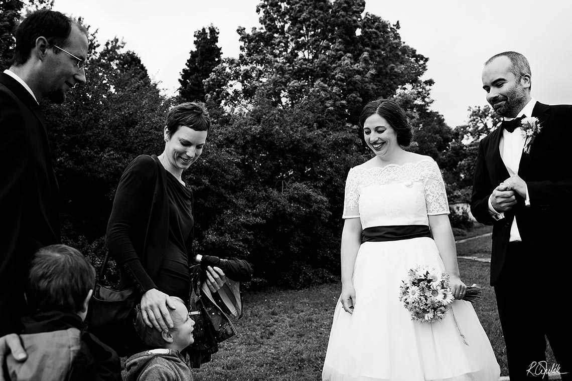 černobílá fotografie momentka ženicha a nevěsty s hosty