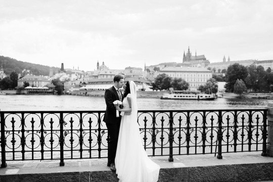 ženich a nevěsta na nábřeží v Praze s výhledem na Pražský hrad